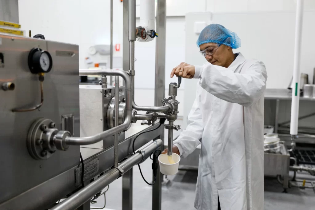 A man in a lab coat pouring milk into a machine.